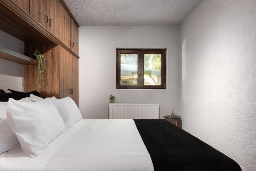 a bedroom with a large white bed with a window at Hidden Stone Chalet in Zarouhla