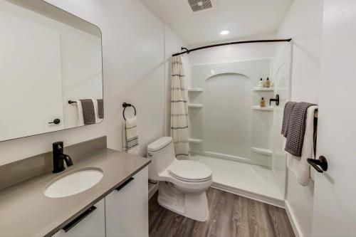 a white bathroom with a toilet and a sink at Brand New Stylish Studio Suite Near Downtown in Oakland