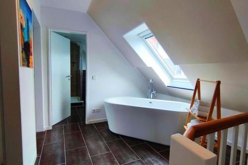 a bathroom with a large white tub in a attic at Ferienhaus an der Elbe - XR32 in Seevetal