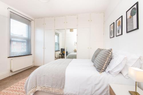 a white bedroom with a large bed and a window at King Room with a shared Kitchen and bathroom in a 5-Bedroom House at Hanwell in Hanwell