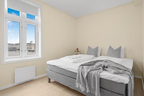 biała sypialnia z łóżkiem i oknem w obiekcie Contemporary city-apartement with views of the dock! w Bergen
