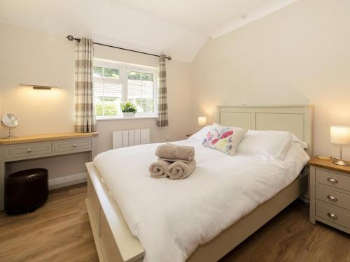 een slaapkamer met een bed met een teddybeer erop bij 2 Luckington Stables-w8322 in Holcombe