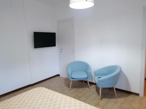 Cette chambre comprend 2 chaises bleues et une télévision. dans l'établissement appartamento Modì, à Pistoia