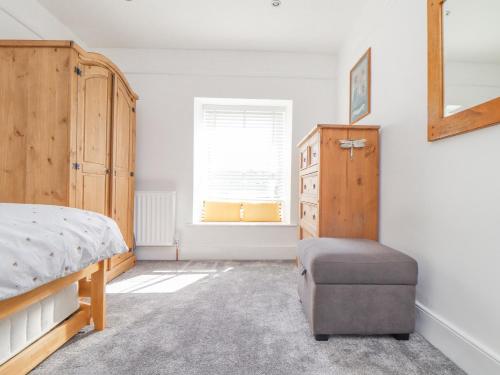 een slaapkamer met een bed en een houten kast bij Dragonfly Cottage in St Austell