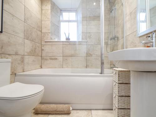 a bathroom with a tub and a toilet and a sink at Dragonfly Cottage in St Austell