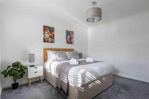 ein weißes Schlafzimmer mit einem Bett und einer Topfpflanze in der Unterkunft The Orange House Langdon Hills 