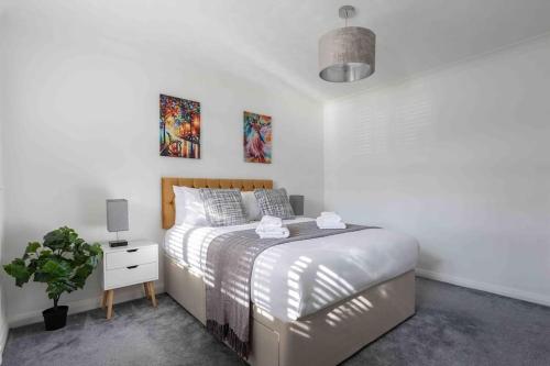 a white bedroom with a bed and a potted plant at The Orange House Langdon Hills 