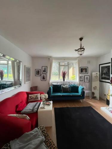 ein Wohnzimmer mit roten und blauen Möbeln und einem Fenster in der Unterkunft Cosy & Chic 1BD Flat - 6 Minutes to Notting Hill! in London