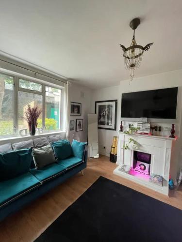 ein Wohnzimmer mit einem blauen Sofa und einem Kamin in der Unterkunft Cosy & Chic 1BD Flat - 6 Minutes to Notting Hill! in London