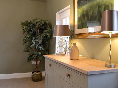 una mesa con dos lámparas y una planta en una habitación en Gardeners Cottage en Montrose