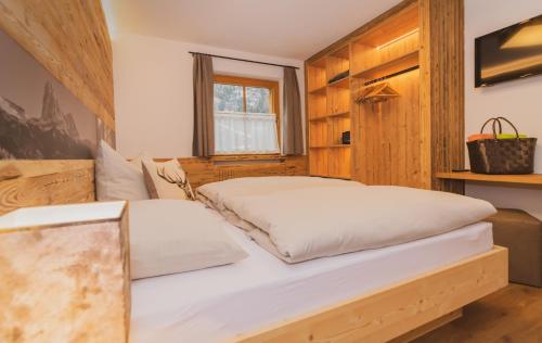 two beds in a bedroom with wooden walls at Alpinchalet Apartment Alpenrose in Ortisei