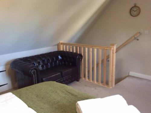 Country Studio Apartment في Charlton: غرفة معيشة مع أريكة جلدية ودرج