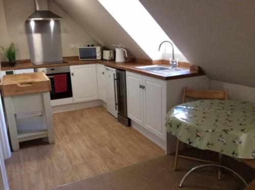 Country Studio Apartment في Charlton: مطبخ بدولاب بيضاء ومغسلة وطاولة