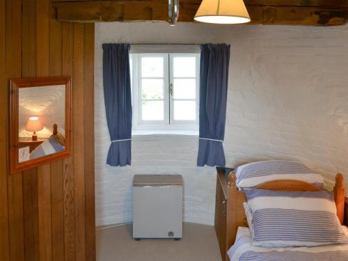 a bedroom with two beds and a window with blue curtains at The Mill The Mill House in Ludham