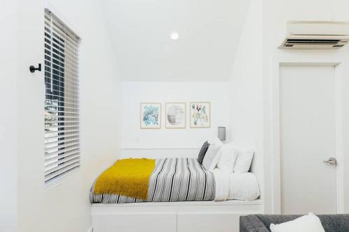 a white bedroom with a bed with a yellow blanket at Luxury Apt in West Oakland - Near Downtown in Oakland