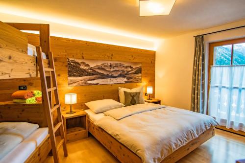 een slaapkamer met een stapelbed en een ladder bij Alpinchalet Apartment Enzian in Ortisei