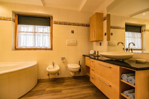 een badkamer met een wastafel, een bad en een toilet bij Alpinchalet Apartment Enzian in Ortisei