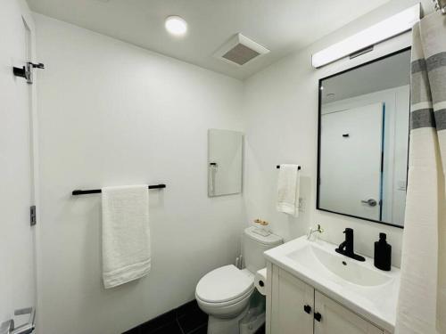 Baño blanco con aseo y lavamanos en Luxury Furnished Studio Suite close to Downtown, en Oakland
