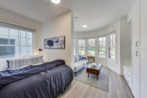 a bedroom with a bed and a couch and windows at Luxury Furnished Studio Suite in Lake Merritt in Oakland