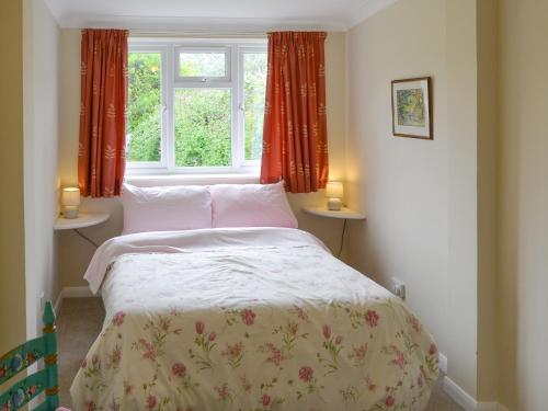 1 dormitorio con 1 cama y una ventana con cortinas rojas en Silverdale en Bacton