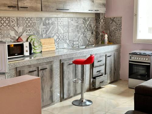 a kitchen with a red stool in front of a counter at Résidences PRIMIS Thiès - appartements et chambres in Thiès