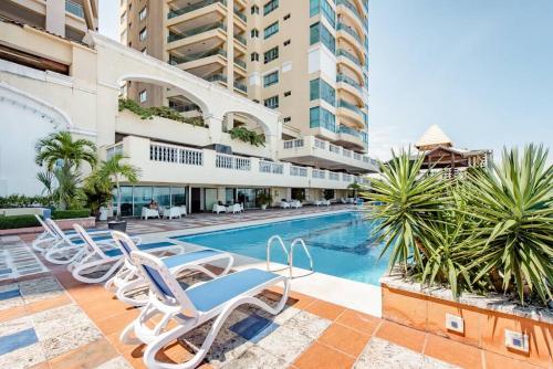 a swimming pool with lounge chairs next to a building at Habitación Privada con vista al mar Ámbar, Malecon Santo Domingo in Santo Domingo