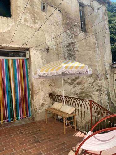 a patio with an umbrella and a bench on a balcony at Appartement de Charme dans un Ancien Mas Cévenol piscine et jacuzzi in Valleraugue