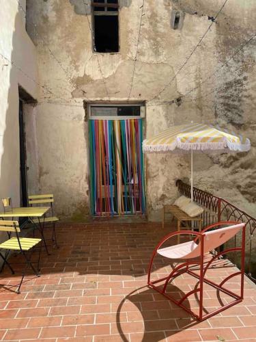 a patio with tables and chairs and an umbrella at Appartement de Charme dans un Ancien Mas Cévenol piscine et jacuzzi in Valleraugue