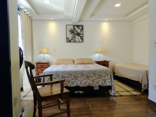 a bedroom with a bed and a chair and a table at Tiradentes Pousada Ramalhete in Tiradentes