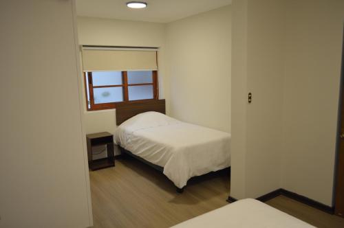 a small bedroom with a bed and a window at Hotel Rukalaf in Chillán