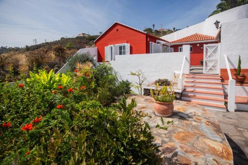 ein rotes und weißes Haus mit einigen Pflanzen und Blumen in der Unterkunft Casa El Drago 2 in Breña Baja
