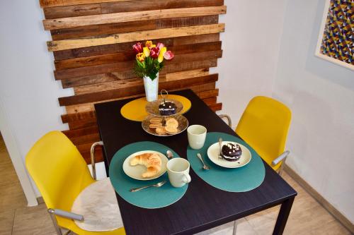 a black table with plates of food and yellow chairs at Bed and Bike Rheine in Rheine