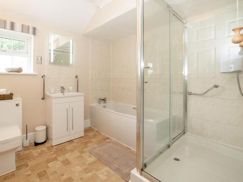 a bathroom with a shower and a tub and a sink at 2 Luckington Stables-w8322 in Holcombe