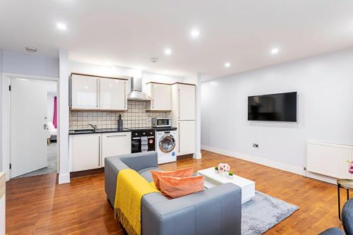 a living room with a couch and a kitchen at Bright St Johns Apartments in London