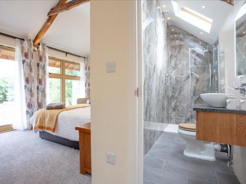 a bedroom with a bed and a bathroom with a sink at Orchard Barn in South Tawton