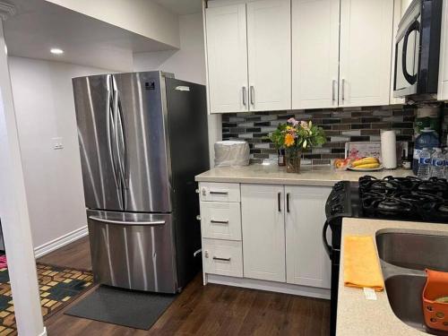a kitchen with a stainless steel refrigerator and white cabinets at one bedroom basement apartment in Milton