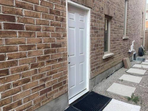 uma parede de tijolos com uma porta branca num edifício em one bedroom basement apartment em Milton