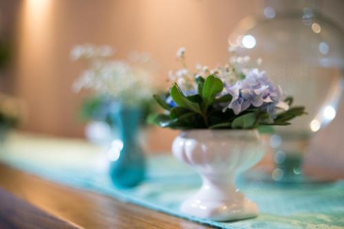 a white vase with flowers in it on a table at Abayomi Hotel in Ilhabela