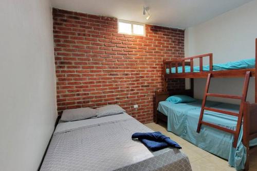 a bedroom with two bunk beds and a brick wall at Agradable casa familiar cerca de Los Frailes in Puerto López