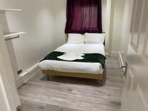 1 dormitorio pequeño con 1 cama con sábanas blancas en W3 Guest House, en Londres