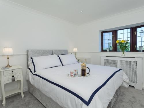 a white bedroom with a large bed with a vase of flowers at Buttercup Cottage in Halsall