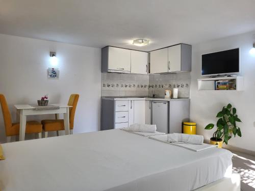 a white bedroom with a large bed and a kitchen at Apartments Teodo in Tivat