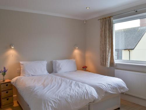 a bedroom with a bed with white sheets and a window at Riverside in Bude