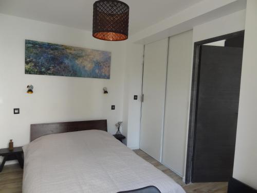 1 dormitorio con 1 cama y una pintura en la pared en Aupetitclos en Vincennes