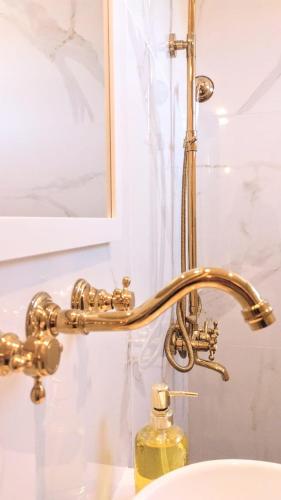 a bathroom sink with a gold shower faucet at La Flor del Camino Posada in Tanti
