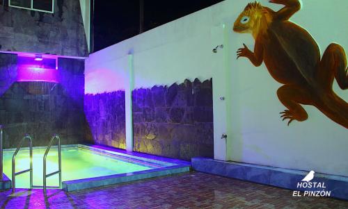 une piscine avec un dinosaure peint sur le mur dans l'établissement Hostal El Pinzón, à Puerto Ayora