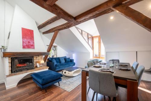 salon ze stołem i krzesłami oraz kominkiem w obiekcie Sous Les Toits d'Annecy, un appartement irrésistible pour 1 à 6 personnes en plein coeur de ville w Annecy