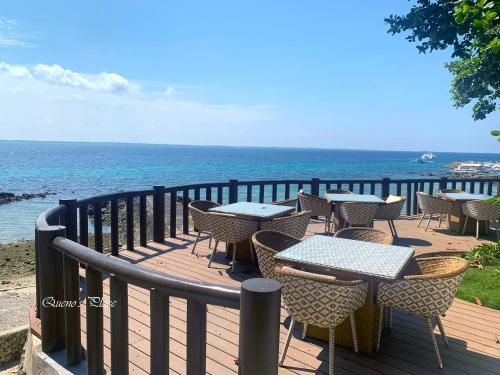 a wooden deck with tables and chairs and the ocean at Mactan Newtown - New Modern Condo with Ocean View in Mactan