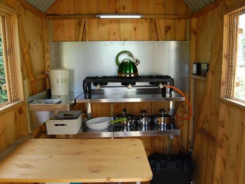 a small kitchen with a stove and a wooden table at Hicks Hut -ukc4753 in Tremeirchion