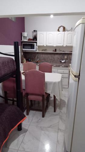 La cuisine est équipée d'une table, de chaises et d'un réfrigérateur. dans l'établissement Casa Canela, à Ezeiza